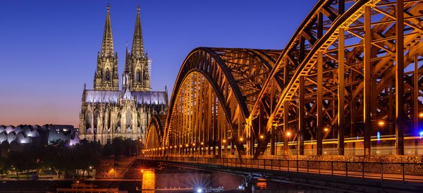 Kölner Dom und beleuchtete Hohenzollernbrücke über den Rhein bei Abenddämmerung in Köln