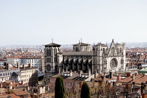 Blick auf die Kathedrale von Lyon mit gotischer Architektur, umgeben von roten Dächern und Stadtgebäuden bei klarem Himmel
