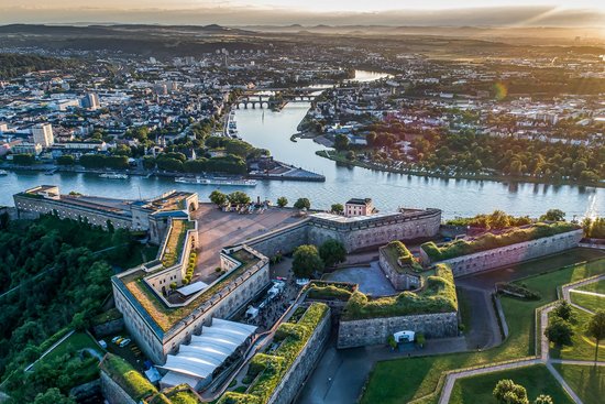 Das Deutsche Eck in Koblenz mit dem Kaiser-Wilhelm-Denkmal, umgeben von Rhein und Mosel, bei Sonnenuntergang.
